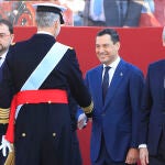 El rey saluda al presidente de Andalucía, Juanma Moreno (2d), en presencia del presidente de Asturias, Adrián Barbón (i), y el presidente de Galicia, Alfonso Rueda (d), al inicio del desfile del Día de la Fiesta Nacional, este miércoles, en Madrid. EFE/Zipi Aragón