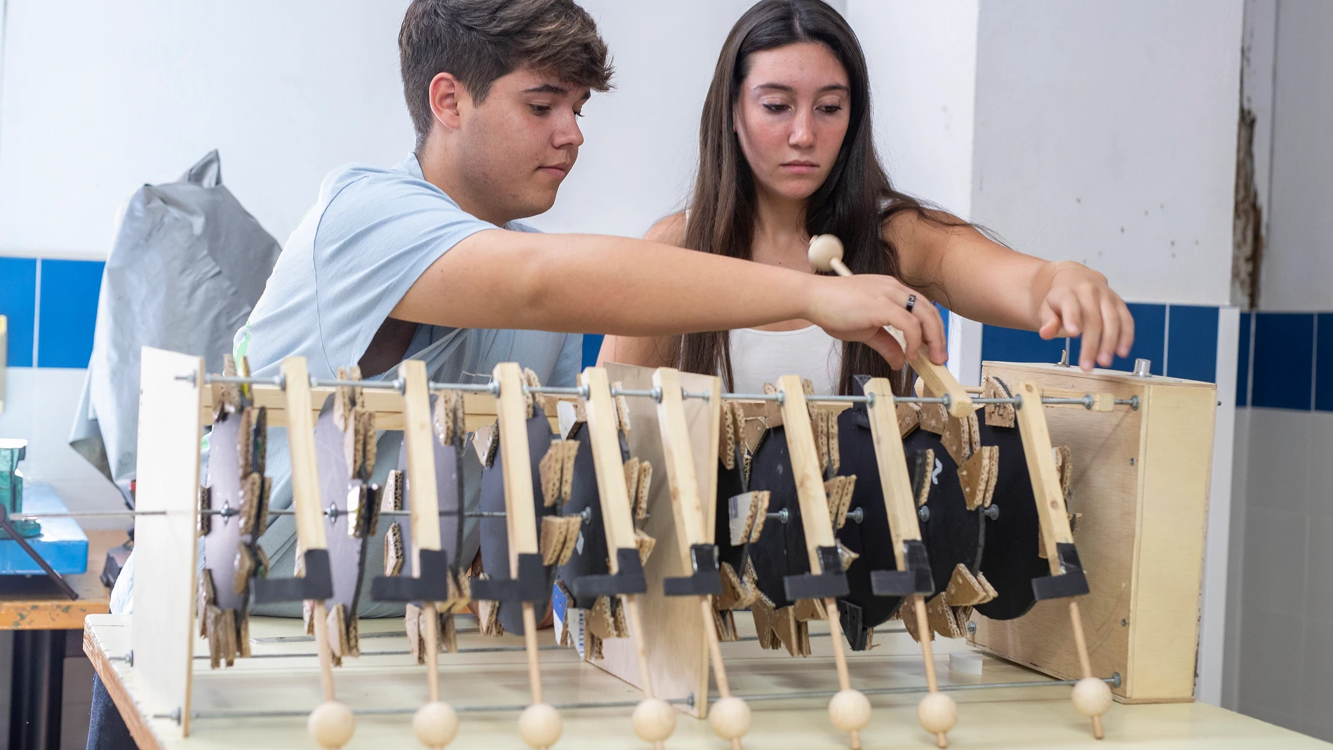 Los alumnos Aarón Reina y Cristina Fernández del IES Almunia de Jerez de la Frontera (Cádiz) junto a la máquina que han diseñado y construido, con materiales reciclados