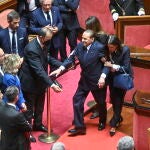 Los ujieres del Senado italiano ayudan ayer a Silvio Berlusconi a llegar a su escaño, en la Cámara Alta