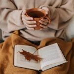 Mujer leyendo un libro con una taza de té en al mano
