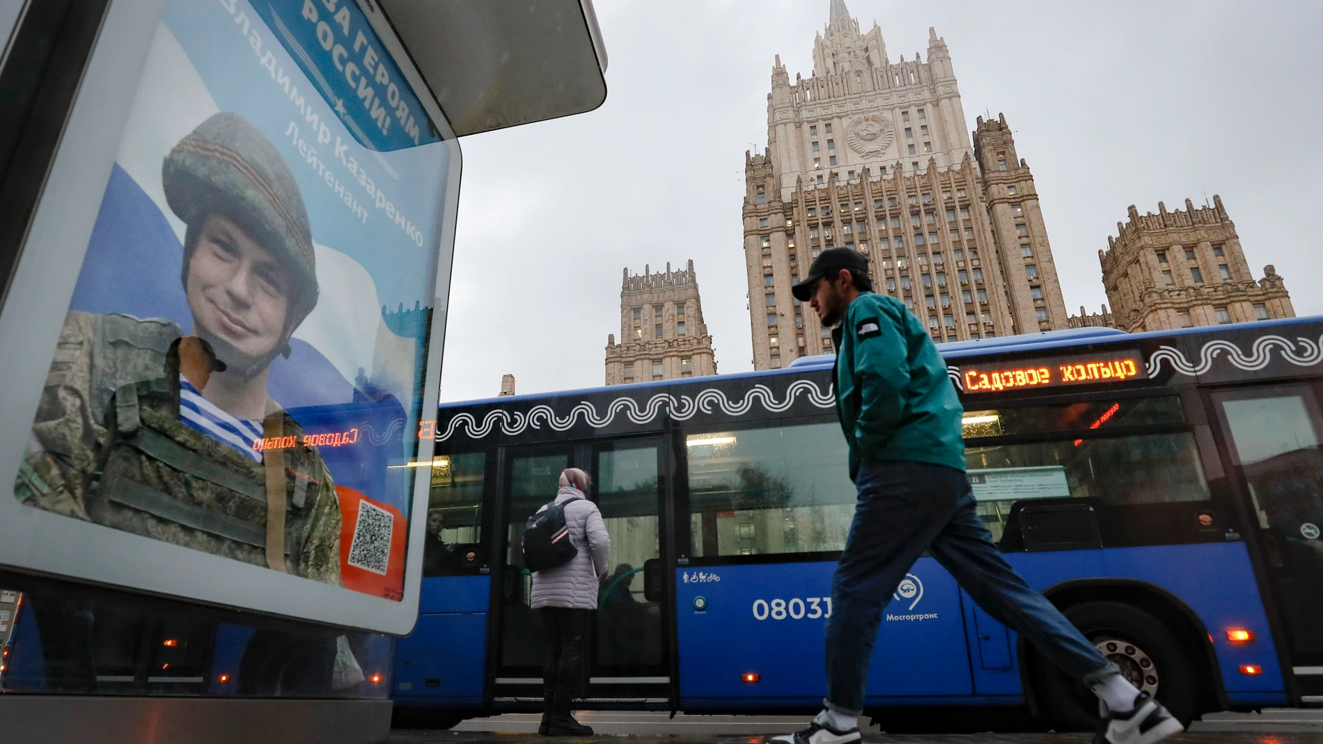 Un hombre pasa junto a un cartel propagandístico que dice «Gloria a los héroes de Rusia» con soldados en el frente