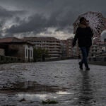 Una mujer se refugia de la lluvia con un paraguas