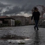 Una mujer se refugia de la lluvia con un paraguas