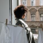 Mujer mirando por la ventana junto a ropa tendida