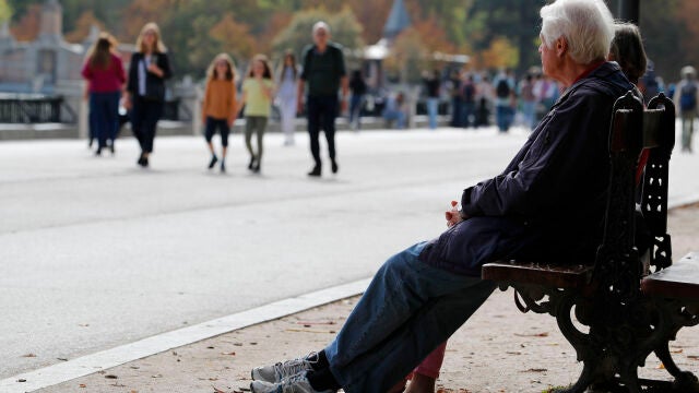Varias personas descansan en un banco del parque de El Retiro de Madrid
