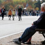 Varias personas descansan en un banco del parque de El Retiro de Madrid