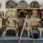 Una mujer coloca un ramo de flores en la lápida de un ser querido en un cementerio