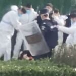 Personal de seguridad con ropa protectora rodea y patea a un manifestante después de que éste agarrara un poste de metal que había sido utilizado para golpearlo durante la protesta en el complejo de la fábrica operada por Foxconn Technology Group, que dirige la mayor fábrica de iPhone de Apple del mundo en Zhengzhou