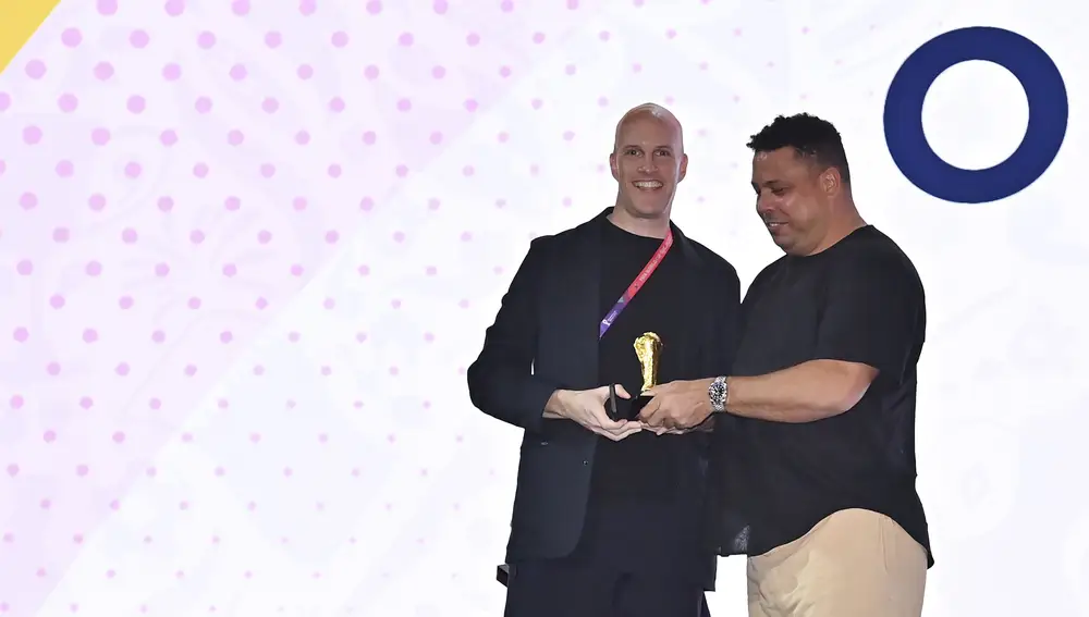 Grant Wahl sonríe cuando la leyenda del fútbol Ronaldo le otorga una réplica del trofeo de la Copa Mundial durante una ceremonia de entrega de premios en Doha