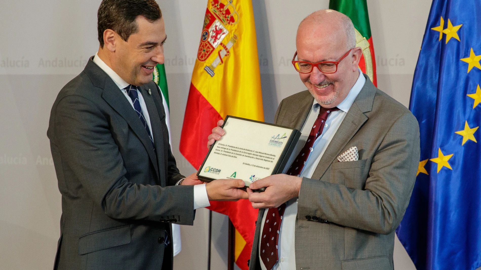 El presidente de la Junta de Andalucía, Juanma Moreno (i), entrega al presidente de la Comisión de Coordinación y Desarrollo Regional del Alentejo y nuevo presidente de la Eurorregión Alentejo-Algarve-Andalucía, António Ceia da Silva, el testigo de la nueva presidencia tras la reunión del Consejo de la Eurorregión Alentejo-Algarve-Andalucía