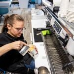 Una persona discapacitada en silla de ruedas trabaja como barista en una cafetería inclusiva