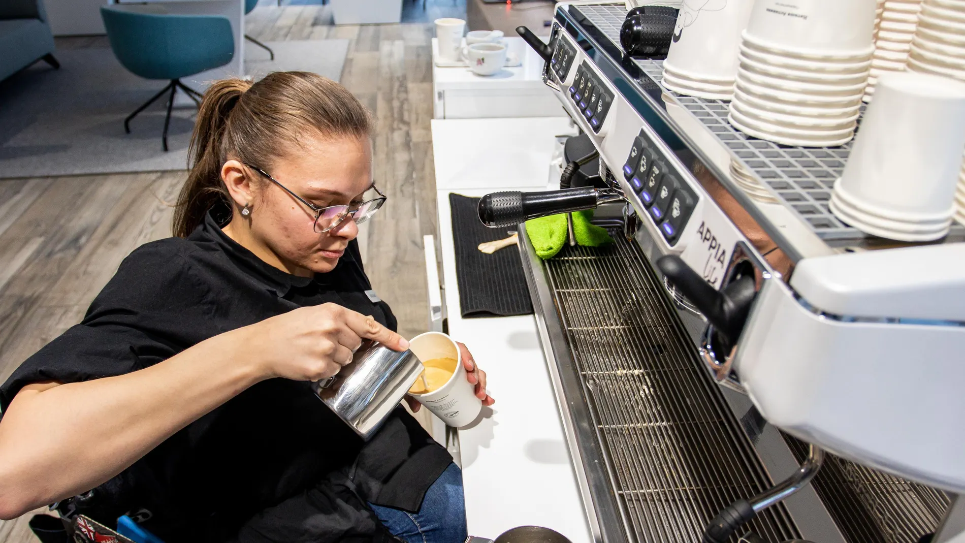Una persona discapacitada en silla de ruedas trabaja como barista en una cafetería inclusiva