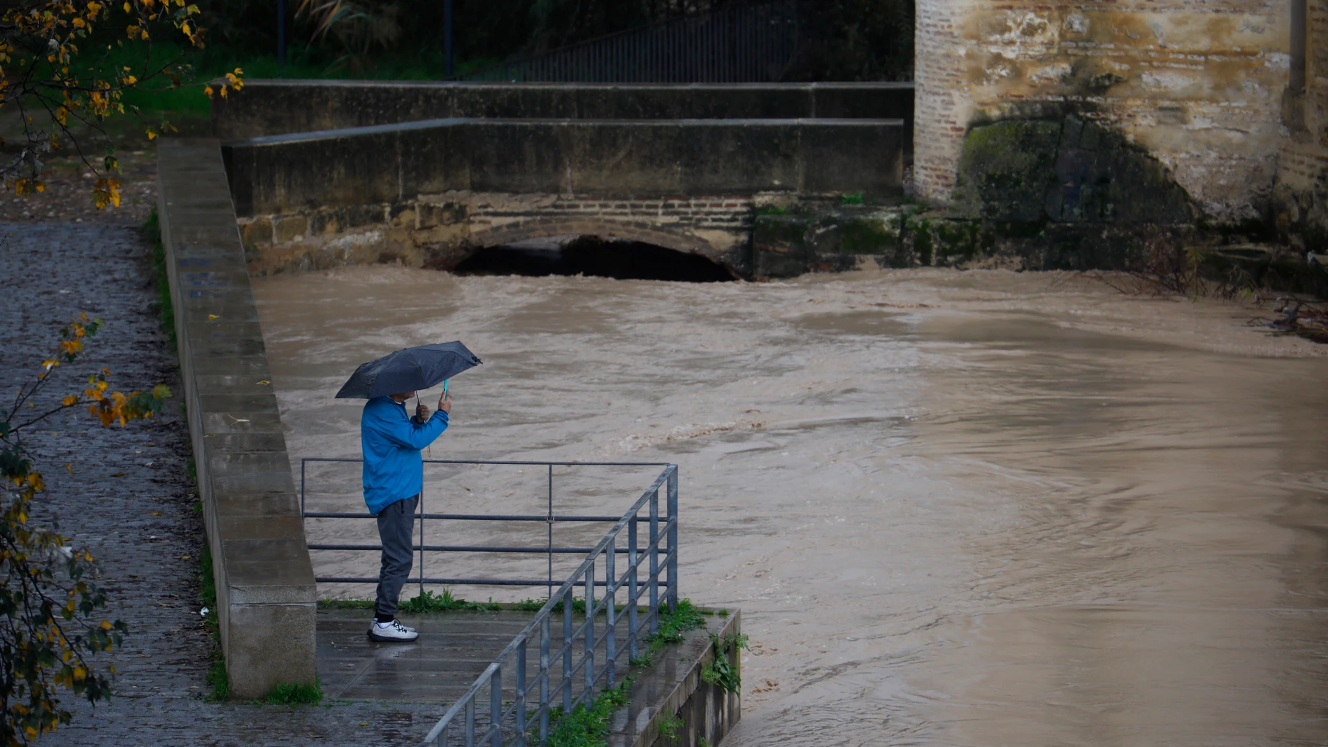 Una persona fotografía el estado en el que se encuentra el río Guadalquivir junto al Puente Romano en Córdoba. EFE/Salas