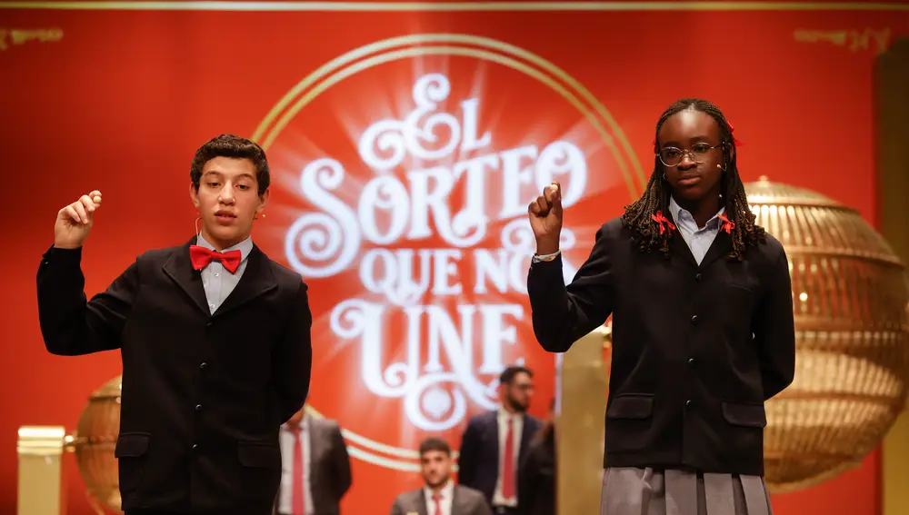 Las estudiantes de San Ildefonso Elisabeth Obarisiagbon Iyamu (d) y su compañero Ilyas Akrouh (i) cantan un quinto premio. EFE/ Javier Lizón