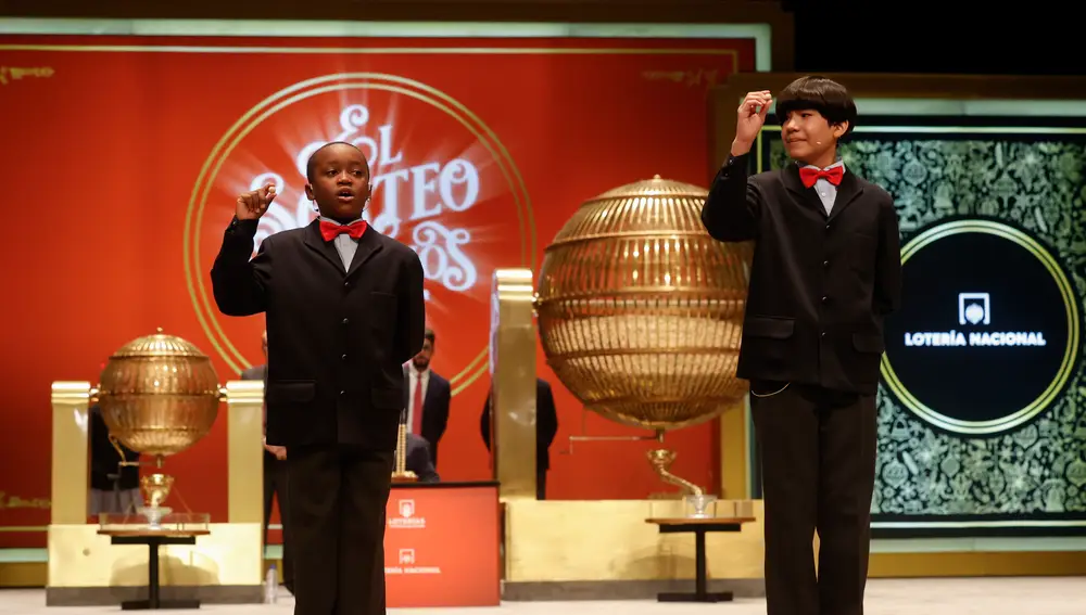 Los estudiantes de San Ildefonso Alonso Dávalos Durán (d) y su compañero Ángel Abaga Elebiyo (i) cantan el premio Gordo durante el sorteo de Navidad en el Teatro Real en Madrid, este jueves