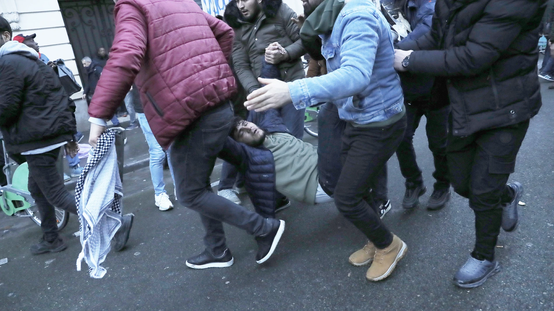 Un hombre que quedó inconsciente durante la protesta es trasladado por varias personas durante un enfrentamiento entre manifestantes y policías en París