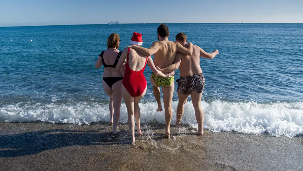 Unos jóvenes se bañan en la playa de la Barceloneta, a 25 de diciembre de 2022, en Barcelona, Cataluña (España).