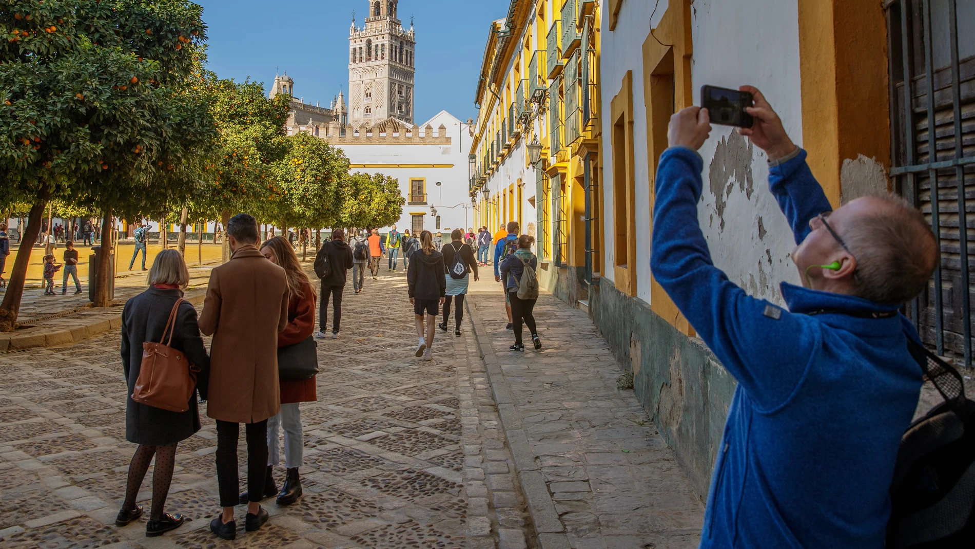Turistas pasean y hacen fotos en el Patio Banderas junto a la Catedral y la Giralda de Sevilla