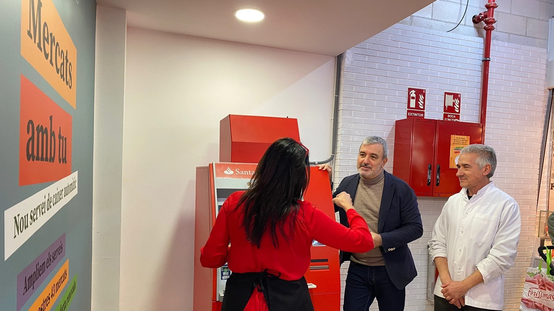 El primer teniente de alcalde de Barcelona, Jaume Collboni, visita el cajero automático en el Mercat del Besòs junto a paradistas