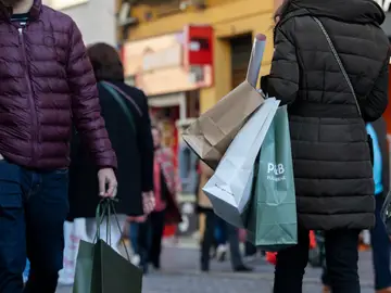 Varias personas con bolsas de la compra en una imagen de archivo Varias personas con bolsas de la compra en una imagen de archivo