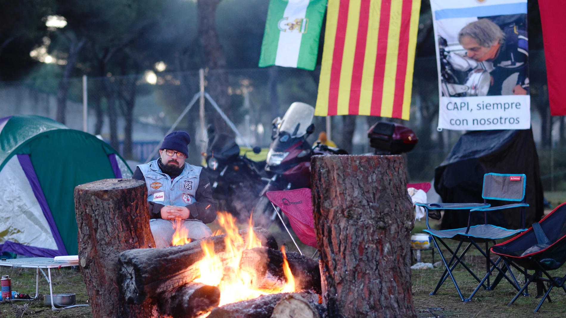 Un motero se calienta en una hoguera en el campamento de la concentración motera invernal Pingüinos 2023