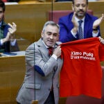 El diputado del PP, Miguel Barrachina, muestra la camiseta que dice: "Ximo Puig. D' ara endavant"