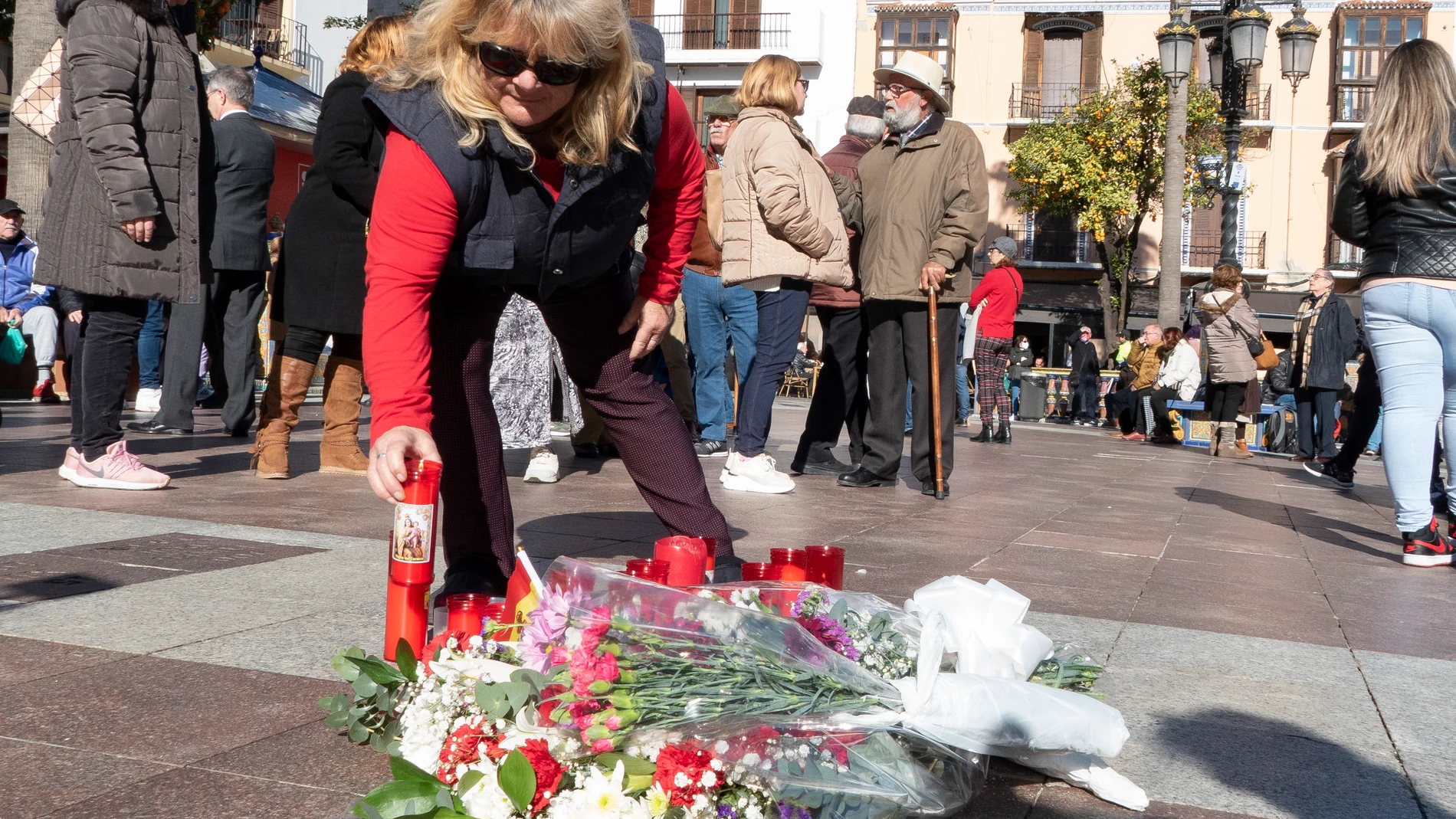 Una mujer coloca una vela en el lugar en el que falleció el sacristán de la iglesia de La Palma, en Algeciras