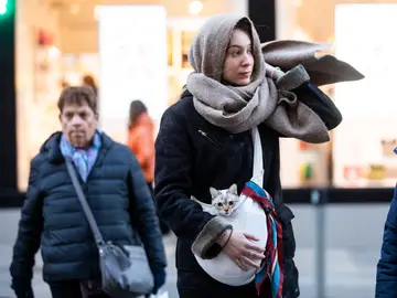 Imagen de una chica que porta un gato, arropados con una bufanda por las bajas temperaturas Imagen de una chica que porta un gato, arropados con una bufanda por las bajas temperaturas