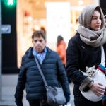 Imagen de una chica que porta un gato, arropados con una bufanda por las bajas temperaturas 