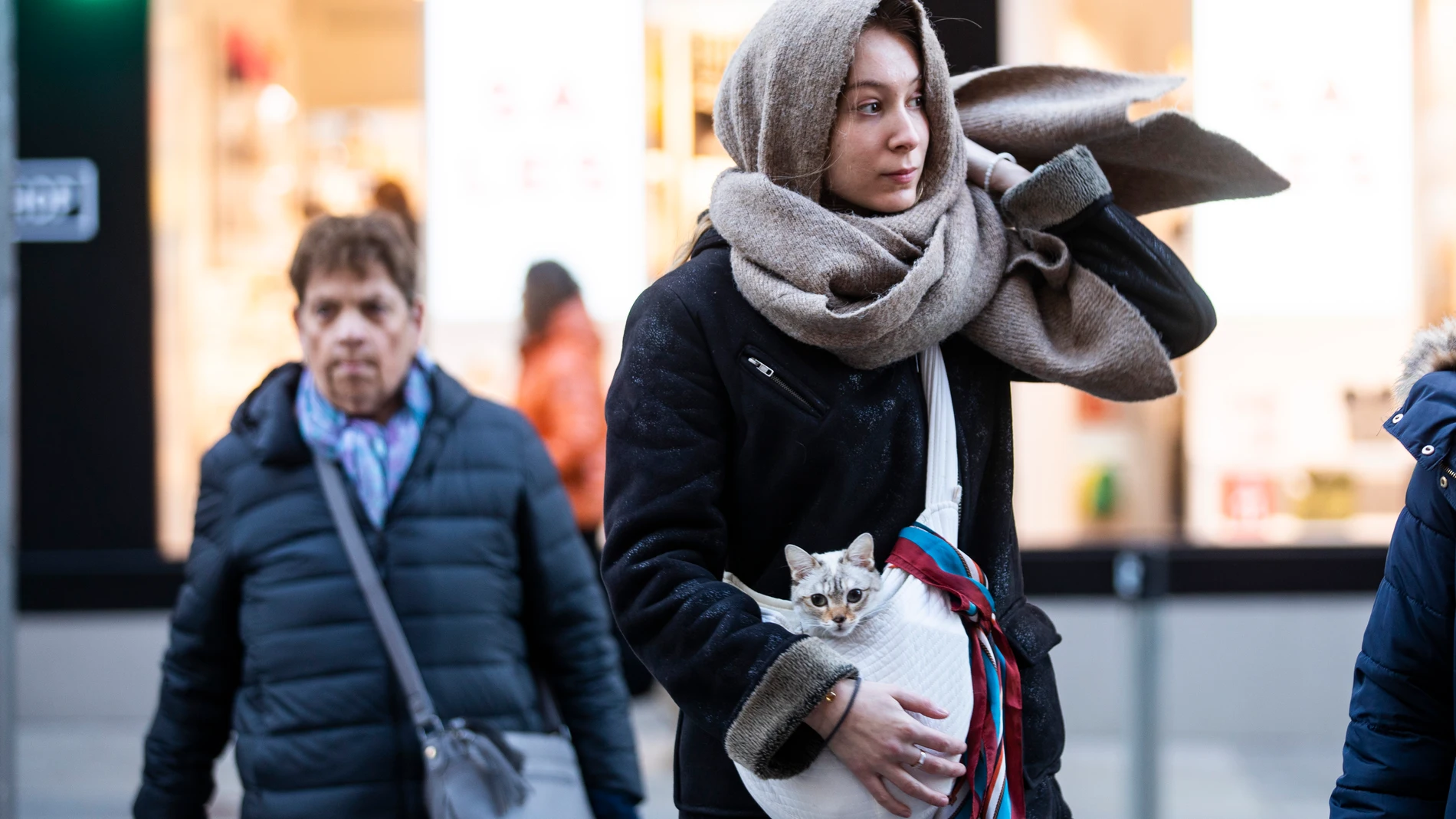 Imagen de una chica que porta un gato, arropados con una bufanda por las bajas temperaturas