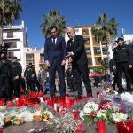 El presidente de la Junta de Andalucía, Juanma Moreno junto con el alcalde de Algeciras, José Ignacio Landaluce, ante las flores y velas dejadas en la plaza en la que fue asesinado el sacristán de la Iglesia de La Palma, Diego Valencia