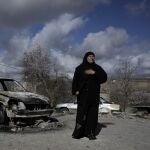 Una mujer palestina junto a un coche quemado en el pueblo de Jalud, cerca de la ciudad cisjordana de Naplusa