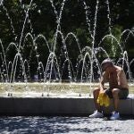 Un hombre descansa al lado de una fuente durante una de las olas de calor en Madrid 