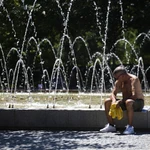 Un hombre descansa al lado de una fuente durante una de las olas de calor en Madrid