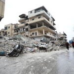 Varias personas caminan cerca de un edificio derrumbado tras un terremoto en la ciudad de Armanaz, en la gobernación siria de Idlib
