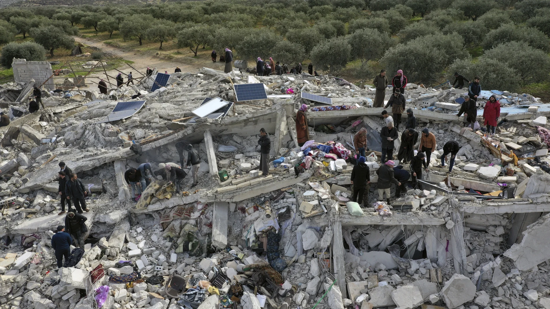 Trabajadores de defensa civil y residentes buscan entre los escombros de edificios derrumbados en la ciudad de Harem, cerca de la frontera turca, provincia de Idlib