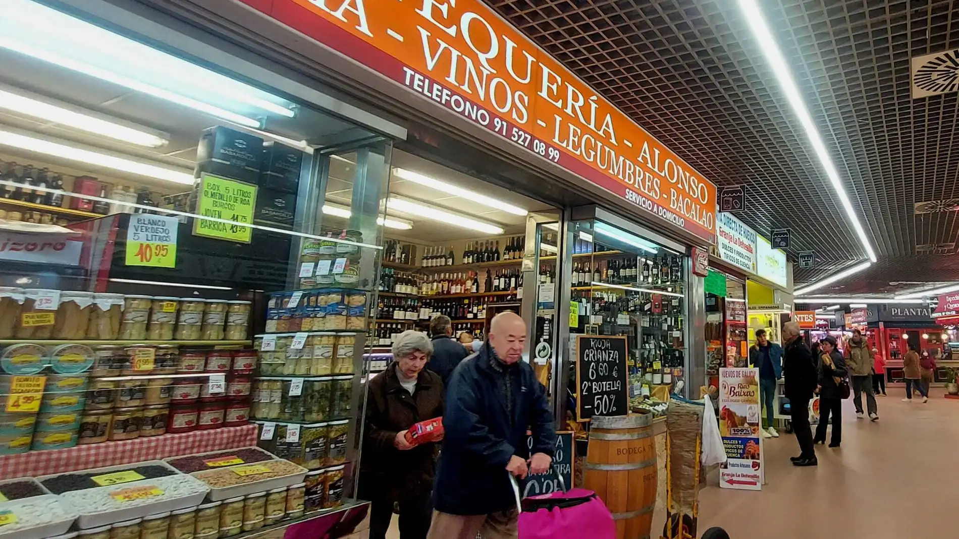 Una pareja de ancianos sale de un pequeño comercio en el Mercado Santa María de la Cabeza en Arganzuela.