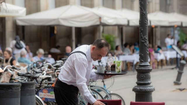 Un camarero limpia una mesa en una terraza 