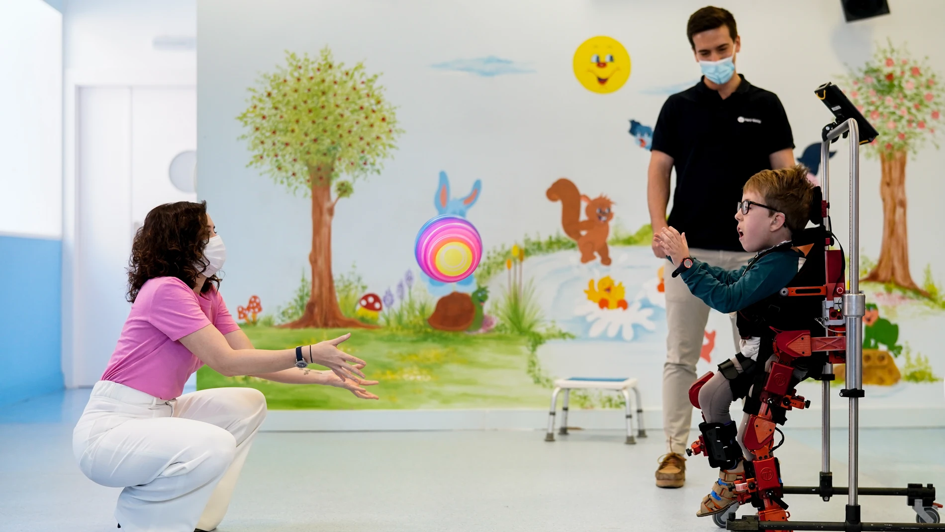 Isabel Díaz Ayuso, juega a la pelota con Adolfo Garcia-Inés, un niño de 9 años que usa el exoesquelero Atlas 2023, en el Hospital Universitario Infantil Niño Jesús