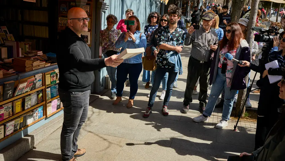 El librero y creador de contenidos en YouTube, Luis Pedrador, anima a leer este lunes mientras el escrito Juan José Saavedra le hace una foto en una de las casetas de libreros de la Cuesta de Moyano.