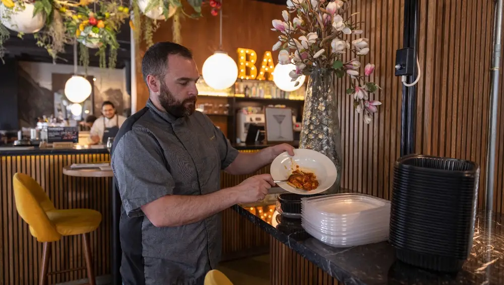 El chef del restaurante Diurno, Luis Miguel Moreno, pasa la comida del plato a uno de los envases de plástico reciclado que usan "cuando se terminan los tápers de Envapro".