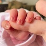 Un bebé agarra la mano de un adulto