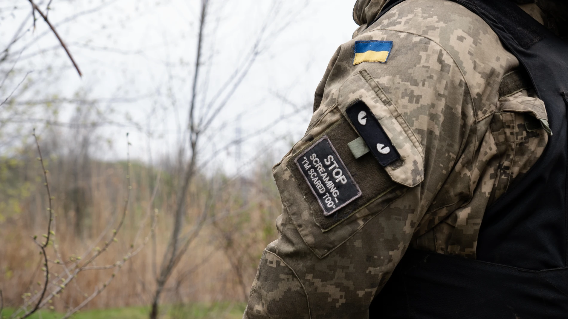April 15, 2023, Bakhmut, Ukraine: A patch written 'stop screaming �I'm scared too'' is seen on a Ukrainian soldier's army uniform, alongside a Ukrainian flag in the Ukrainian position near Bakhmut. Ukrainian armed force is fighting intensely in Bakhmut and the surrounding area as Russian forces are getting ever closer to taking the eastern city of Ukraine. The battle of Bakhmut is now known as 'the bloodiest' and 'one of the longest fight', it has become one of the most significant fights in the war between Ukraine and Russia. 15/04/2023