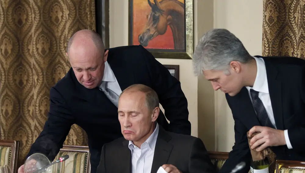 Businessman Yevgeny Prigozhin, left, serves food to Russian Prime Minister Vladimir Putin, center, during dinner at Prigozhin's restaurant outside Moscow, Russia, Friday, Nov. 11, 2011.