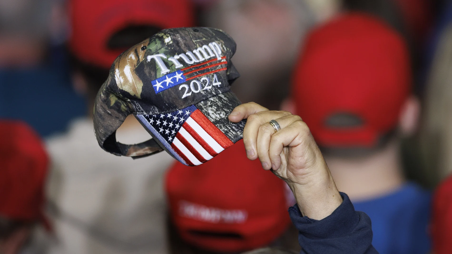 A supporter of former US president Donald Trump, waves a Trump 2024 campaign hat, before Trump addressed a crowd during a rally in Manchester, New Hampshire, USA