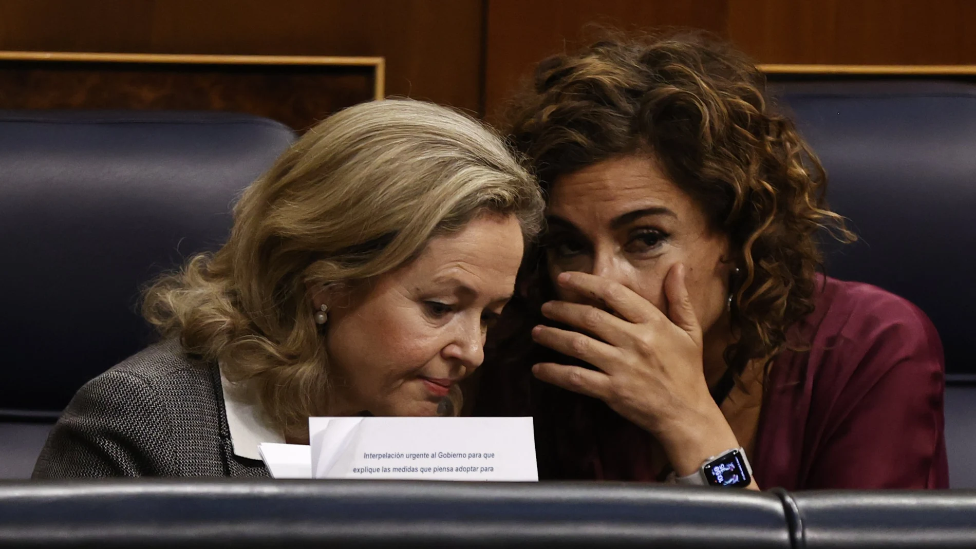 La vicepresidenta primera y ministra de Asuntos Económicos y Transformación Digital, Nadia Calviño (i), conversa con la ministra de Hacienda, María Jesús Montero (d), durante un pleno que se celebra, en el Congreso de los Diputados.