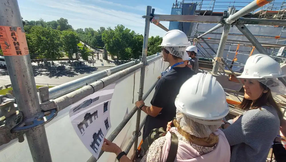 Varios visitantes observan el Parque de El Retiro y la calle Alcalá desde lo alto de la Puerta de Alcalá este sábado en la primera visita a las obras de conservación de la iniciativa 'Abierto por restauración' tras las visitas del verano pasado a los estudios previos.