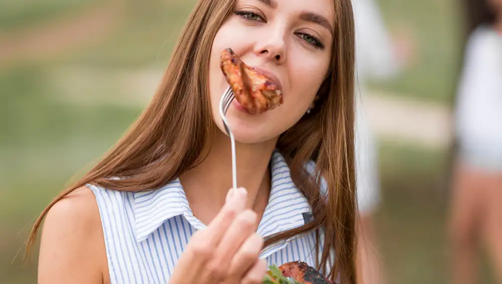 Mujer comiendo un filete de carne