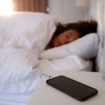 Un teléfono móvil cargando mientras una chica descansa