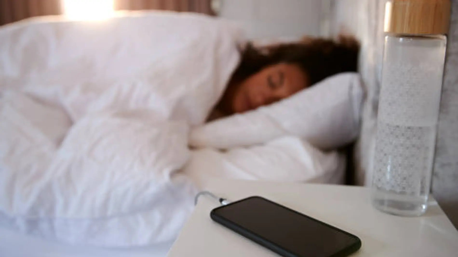 Un teléfono móvil cargando mientras una chica descansa